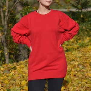 May include: A bright red oversized sweater with long sleeves and a crew neck.