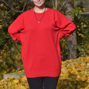 May include: A red oversized sweater with long sleeves and a crew neck.