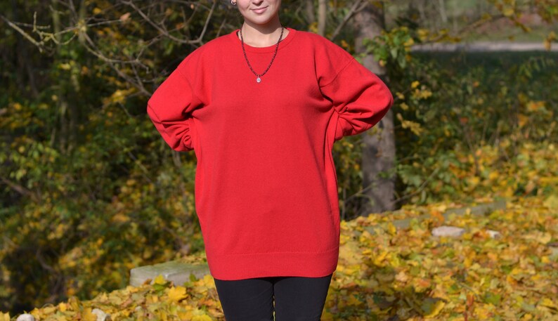 May include: A red oversized sweater with long sleeves and a crew neck.