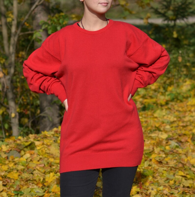 May include: A bright red oversized sweater with long sleeves and a crew neck.