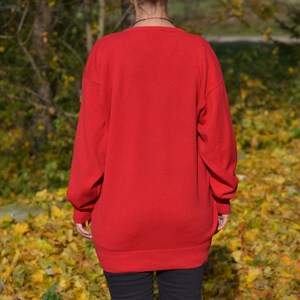 May include: A red long-sleeved sweater with a crew neck.