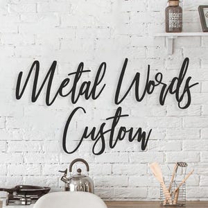 May include: Black metal words "Metal Words Custom" on a white brick wall background.