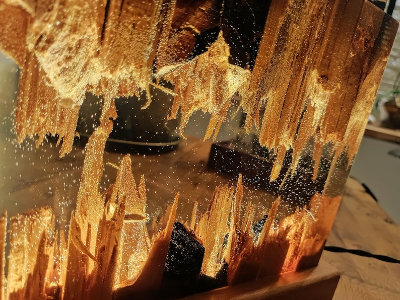 The Fission Resin Lamp, an Epoxy Resin Nightlamp with Oak Wood & Resin Decor, is a Wooden Modern Table Lamp ideal for home decor. This Resin Nightstand Lamp combines natural oak and epoxy resin, offering a sleek, contemporary glow for your nightstand or living space in a unique, handcrafted design.