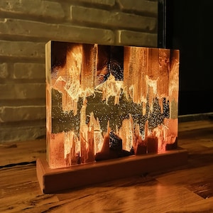 The Fission Resin Lamp, an Epoxy Resin Nightlamp with Oak Wood & Resin Decor, is a Wooden Modern Table Lamp ideal for home decor. This Resin Nightstand Lamp combines natural oak and epoxy resin, offering a sleek, contemporary glow for your nightstand or living space in a unique, handcrafted design.