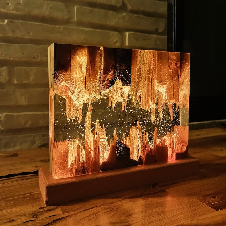 The Fission Resin Lamp, an Epoxy Resin Nightlamp with Oak Wood & Resin Decor, is a Wooden Modern Table Lamp ideal for home decor. This Resin Nightstand Lamp combines natural oak and epoxy resin, offering a sleek, contemporary glow for your nightstand or living space in a unique, handcrafted design.