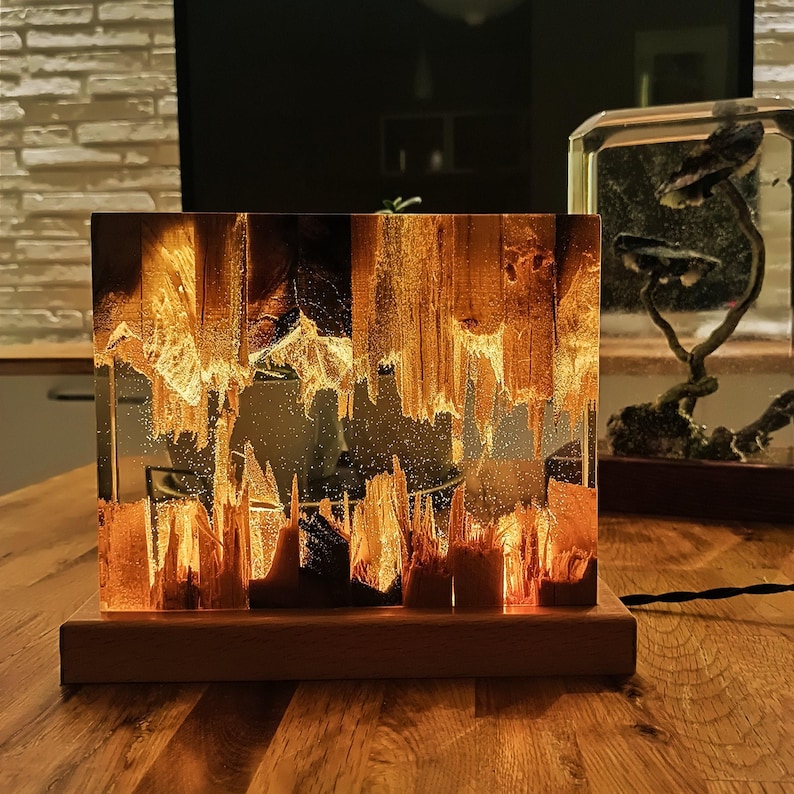 The Fission Resin Lamp, an Epoxy Resin Nightlamp with Oak Wood & Resin Decor, is a Wooden Modern Table Lamp ideal for home decor. This Resin Nightstand Lamp combines natural oak and epoxy resin, offering a sleek, contemporary glow for your nightstand or living space in a unique, handcrafted design.