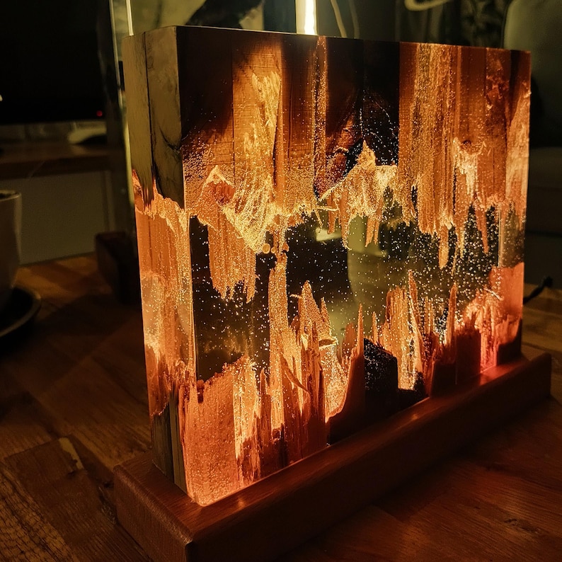 The Fission Resin Lamp, an Epoxy Resin Nightlamp with Oak Wood & Resin Decor, is a Wooden Modern Table Lamp ideal for home decor. This Resin Nightstand Lamp combines natural oak and epoxy resin, offering a sleek, contemporary glow for your nightstand or living space in a unique, handcrafted design.