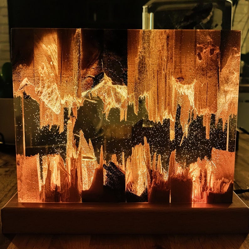 The Fission Resin Lamp, an Epoxy Resin Nightlamp with Oak Wood & Resin Decor, is a Wooden Modern Table Lamp ideal for home decor. This Resin Nightstand Lamp combines natural oak and epoxy resin, offering a sleek, contemporary glow for your nightstand or living space in a unique, handcrafted design.