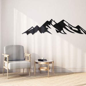May include: Black metal mountain range wall decor in a living room setting with a gray armchair and a gold side table.