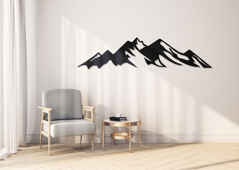 May include: Black metal mountain range wall decor in a living room setting with a gray armchair and a gold side table.