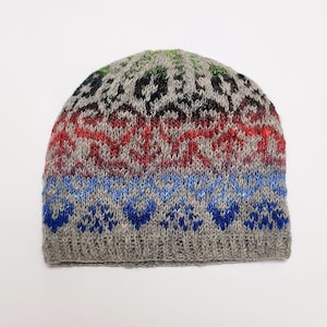 May include: A gray knitted beanie with a colorful pattern. The pattern includes red, blue, green, and black. The beanie is made of wool and has a soft, comfortable feel.