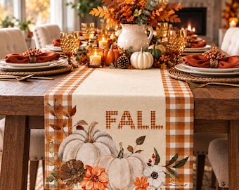 May include: A rectangular table runner featuring a beige center with the word FALL printed in a brown plaid pattern. The runner displays illustrations of two white pumpkins and orange flowers, framed by orange and white checkered borders.