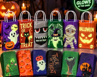Peut inclure: Une collection de sacs cadeaux en papier colorés sur le thème d'Halloween, avec des fantômes, des citrouilles, des momies et des chauves-souris. Les sacs ont des anses blanches et certains portent l'inscription Trick or Treat ou Halloween. Un badge indique qu'ils brillent dans le noir.