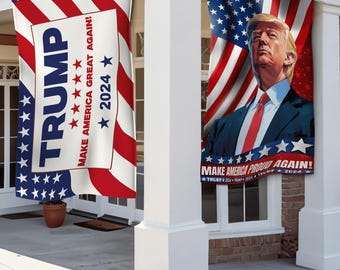 Könnte beinhalten: Zwei amerikanische Flaggenbanner mit dem Text "TRUMP" und "MAKE AMERICA GREAT AGAIN!" und "MAKE AMERICA PROUD AGAIN!" mit einem Porträt von Donald Trump auf einem Banner.