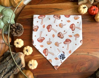Op de afbeelding: Een witte bandana met een bruin paddenstoel- en bladmotief. De bandana heeft een klein pootje-logo in de rechterbenedenhoek.