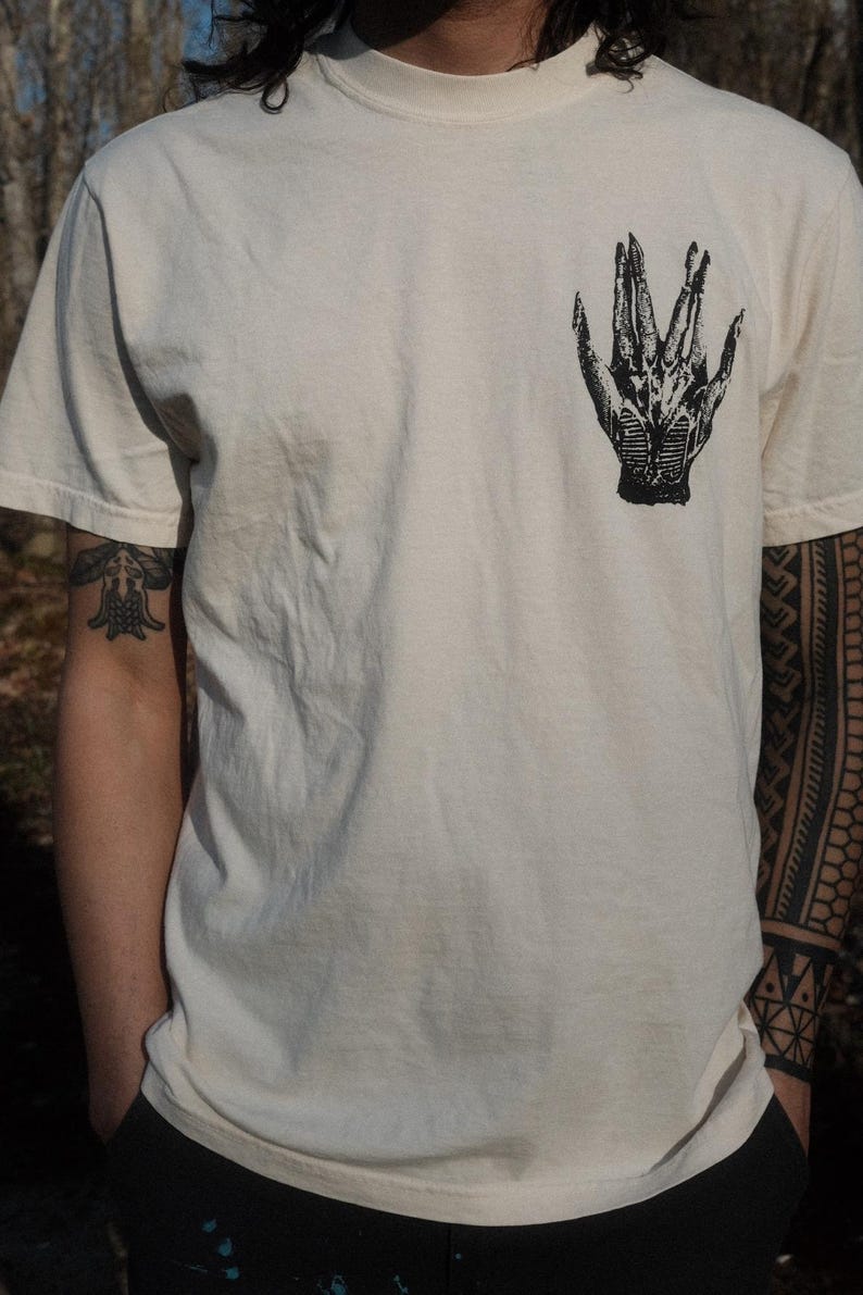 May include: A white t-shirt with a black and white graphic of a hand on the front.