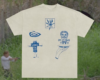 Op de afbeelding: Crèmekleurig T-shirt met blauwe grafische ontwerpen. Het shirt heeft verschillende illustraties, waaronder een spiraal, een geometrische vorm, een figuur met een bord en een robotachtig figuur met de tekst "LONE TA".