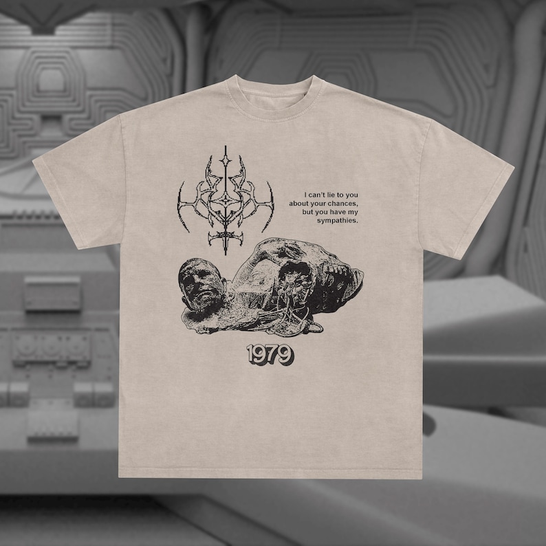 May include: A beige t-shirt with a black graphic print of a skull and a quote that reads "I can't lie to you about your chances, but you have my sympathies." The graphic also includes the year "1979".