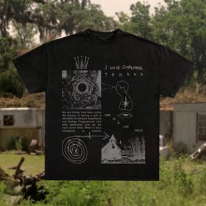 Könnte beinhalten: Schwarzes T-Shirt mit einem verwitterten Grafikdesign. Das Design beinhaltet eine Krone, ein kreisförmiges Muster, eine Silhouette und den Text "I said Darkness, yeahhh". Zusätzlicher Text ist ebenfalls vorhanden.