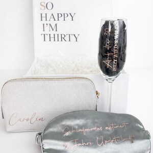 Personalisierte Geschenkbox zum 30. Geburtstag mit Schlafmaske, Kosmetiktasche und Sektglas vor hellem, minimalistischem Hintergrund – Geschenkidee für Frauen