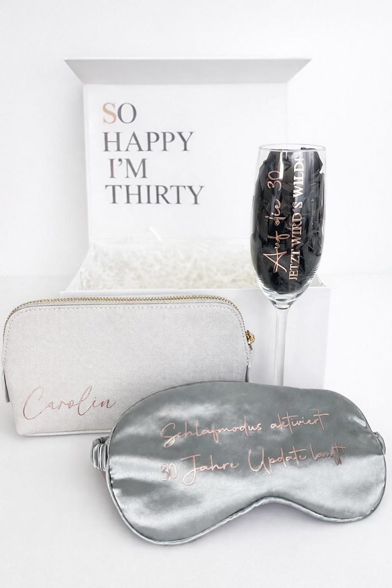 Personalisierte Geschenkbox zum 30. Geburtstag mit Schlafmaske, Kosmetiktasche und Sektglas vor hellem, minimalistischem Hintergrund – Geschenkidee für Frauen