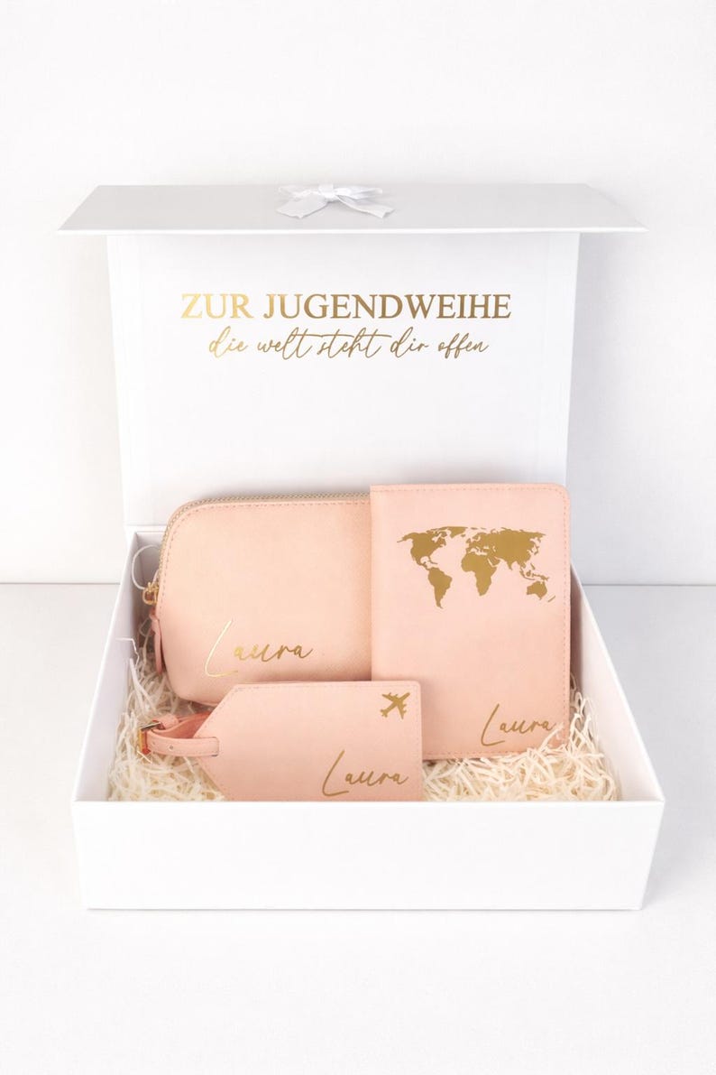 Personalisierte Geschenkbox zur Jugendweihe mit rosa Reise-Set aus Kosmetiktasche, Reisepasshülle und Kofferanhänger mit Name Laura in Gold, dekorativ in weißer Box arrangiert