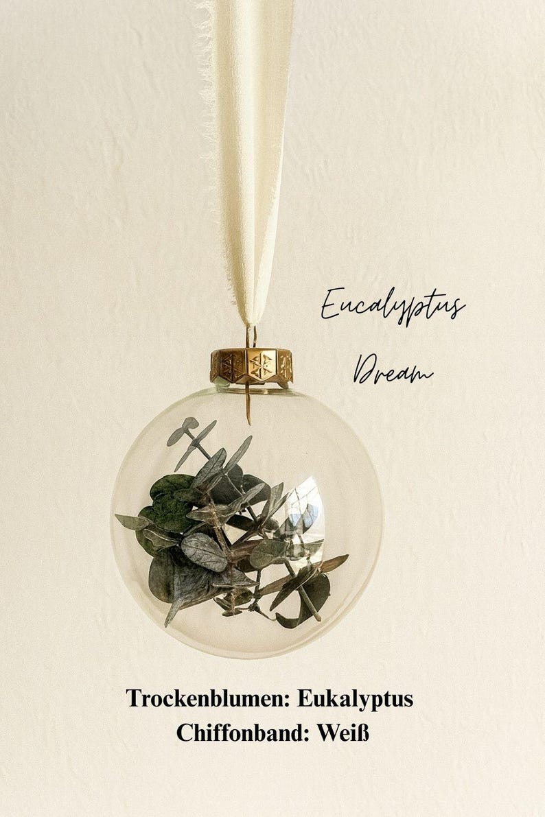 Personalisierte Weihnachtskugel aus Glas mit goldenem Kranz und weißen Chiffon-Aufhänger, gefüllt mit Eukalyptus-Trockenblättern, Variante ‚Eucalyptus Dream‘.