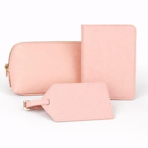 Reiseset in Rosa bestehend aus Reisepasshülle, Kosmetiktasche und Kofferanhänger auf hellem neutralem Hintergrund ohne Personalisierung