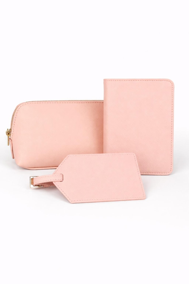 Reiseset in Rosa bestehend aus Reisepasshülle, Kosmetiktasche und Kofferanhänger auf hellem neutralem Hintergrund ohne Personalisierung