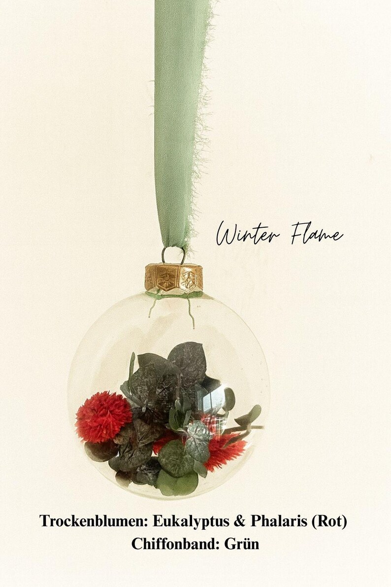 Personalisierte Weihnachtskugel aus Glas mit goldenem Kranz und grünen Chiffon-Aufhänger, gefüllt mit roten Phalaris-Trockenblumen und grünem Eukalyptus, Variante ‚Winter Flame‘.