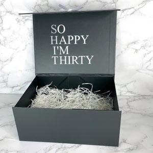 Hochwertige schwarze Geschenkbox zum 30. Geburtstag für Männer, mit weißem Schriftzug 'So Happy I'm Thirty' auf dem Deckel.