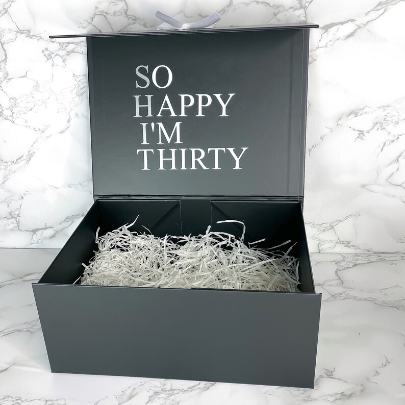 Hochwertige schwarze Geschenkbox zum 30. Geburtstag für Männer, mit weißem Schriftzug 'So Happy I'm Thirty' auf dem Deckel.