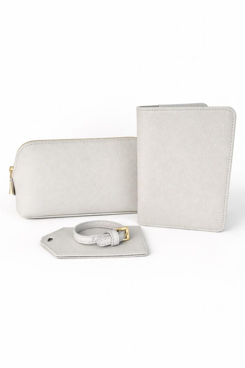 Reiseset in Hellgrau mit Kosmetiktasche, Reisepasshülle und Kofferanhänger auf hellem, neutralem Hintergrund