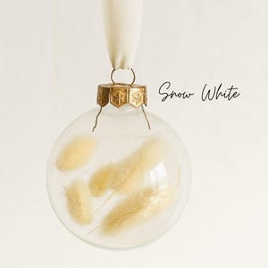 Personalisierte Weihnachtskugel aus Glas mit goldenem Kranz und weißen Chiffon-Aufhänger, gefüllt mit weißen Lagurus-Trockenblumen, Variante ‚Snow White‘.