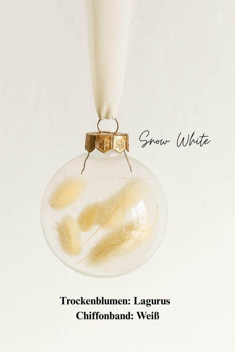 Personalisierte Weihnachtskugel aus Glas mit goldenem Kranz und weißen Chiffon-Aufhänger, gefüllt mit weißen Lagurus-Trockenblumen, Variante ‚Snow White‘.