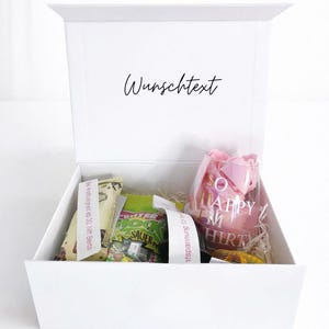 Offene weiße Geschenkbox mit Beispiel-Füllung und personalisiertem Innendruck ‚Wunschtext‘ im Deckel