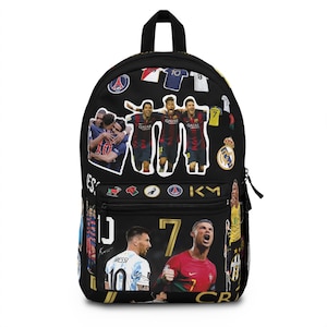 May include: Black backpack featuring images of soccer players and team logos. The backpack has a top handle, a front pocket, and a zipper closure. The design includes images of Messi, Ronaldo, and other soccer stars.