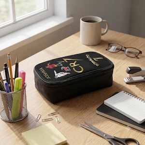May include: A black rectangular pencil case featuring the gold text CR7 and RONALDO 7, along with the name JOSHUA and small graphic illustrations of a soccer player in various poses printed on the top surface of the zippered fabric container.