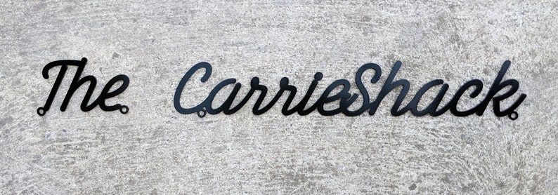 May include: Black metal sign with the text "The Carrie Shack" in a cursive font.