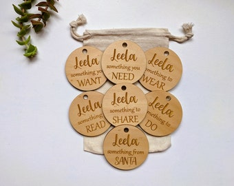 May include: Seven wooden gift tags with the name "Leela" and different phrases, such as "something you want", "something you need", and "something to share".