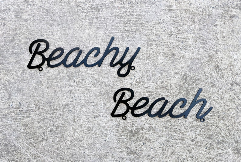 May include: Black metal wall decor with the words "Beachy Beach" in a cursive font.
