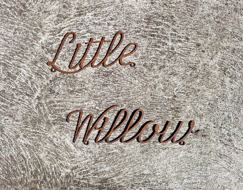 May include: Close-up of a rustic, gray surface with the words "Little Willow" written in rusty metal letters.