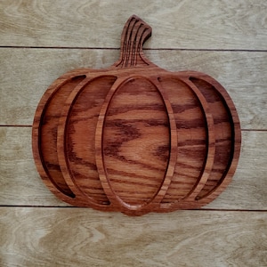 May include: A wooden pumpkin-shaped serving tray with four compartments. The tray is made of dark red wood with a natural wood grain.