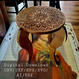 Puede incluir: Un taburete de madera con una parte superior redonda que presenta un diseño de mandala cortado con láser. El taburete tiene tres patas con un diseño curvo. Descarga digital: CRV/DXF/EPS/SVG/AI/PDF