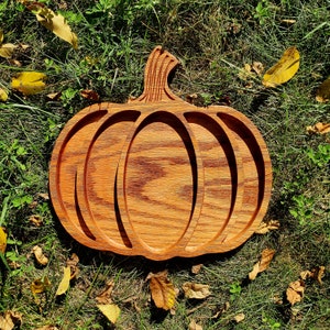 May include: A wooden pumpkin-shaped serving tray with three sections. The tray is made of light brown wood with a reddish-brown stain.