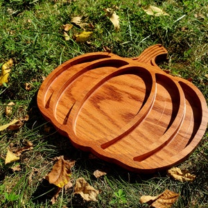 May include: A wooden pumpkin-shaped serving tray with three sections. The tray is made of light brown wood with a natural wood grain finish.