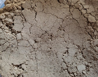 May include: A close-up view of a container filled with a light brown powder. The powder has a slightly grainy texture and is evenly distributed throughout the container.