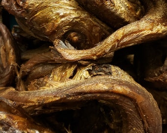 May include: A close-up of a pile of dried fish. The fish are brown and have a rough texture. They are arranged in a random pattern.