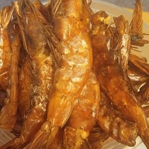 May include: A bowl of cooked, golden brown shrimp. The shrimp are piled high in the bowl and have a glossy sheen.