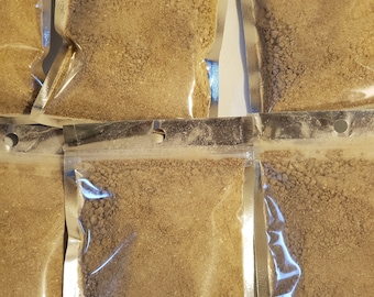 May include: Multiple clear plastic bags filled with a light brown powder. The bags are sealed and have a silver backing.